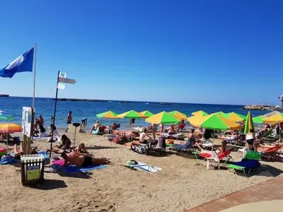 a crowd of people sitting on a beach with umbrellas at Seafront Apartment in Chania 6 in Chania Town