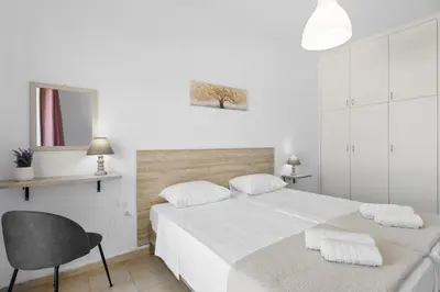 a white bedroom with a bed and a chair at Seafront Apartment in Chania 6 in Chania Town