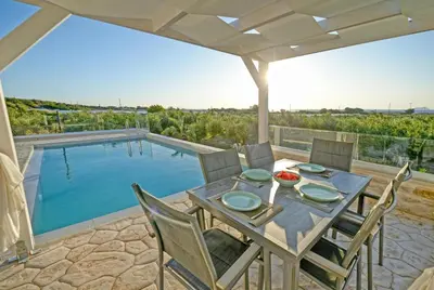 a dining room with a table and chairs and a pool at Koukis Villa With Sea View in Falasarna