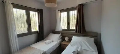 two beds in a room with two windows at Casa di Laino in Kounoupidhianá