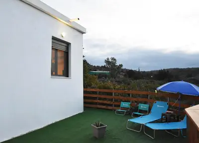 a patio with two blue chairs and an umbrella at Georgia's Dream House in Koprána