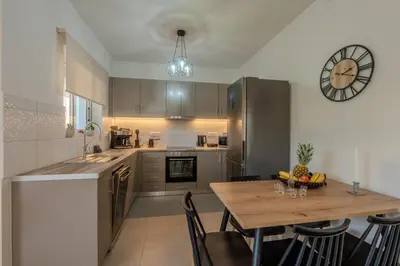 a kitchen with a table and a clock on the wall at Heart Of Galatas Apartments Holidays In crete in Galatás