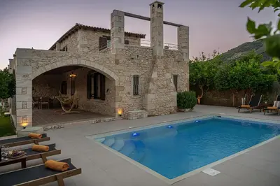 a swimming pool in front of a stone house at Villa Staria in Kirtomádhos