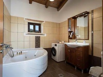 a bathroom with a tub and a sink and a washing machine at Villa Staria in Kirtomádhos