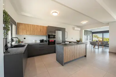 a kitchen with stainless steel appliances and a living room at Villa Aurora 1- Getaway Bliss in Xamoudhokhórion
