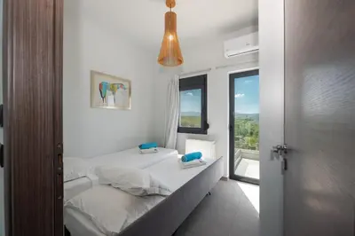 a white bedroom with a bed and a window at Villa Aurora 1- Getaway Bliss in Xamoudhokhórion