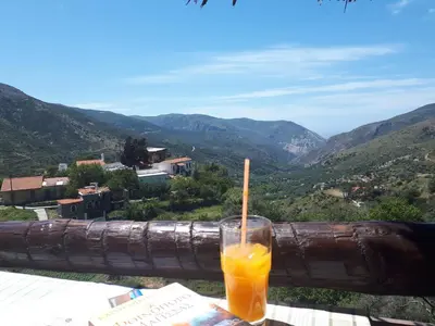 a drink sitting on a table with a view of mountains at Panorama Apartment in Kefálion