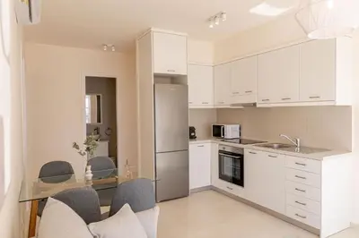 a kitchen with white cabinets and a glass table at Phaedrus Living Seaside Thalassa Cretan 202 in Módhion