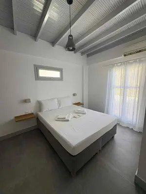 a bedroom with a large white bed with a window at Nikolas Rooms in Loutro