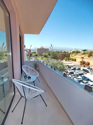 a balcony with two chairs and a view of a parking lot at Bay view in town in Chania Town