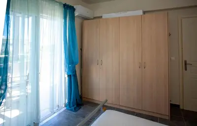 a bedroom with a blue curtain and a large window at Pyrgos Spring pool apartment in Maleme