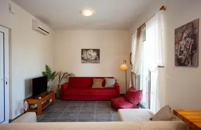 a living room with a red couch and a tv at Pyrgos Spring pool apartment in Maleme