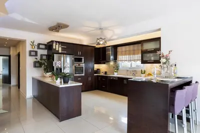 a kitchen with dark wood cabinets and purple bar stools at SI-EL Villa in Vryses