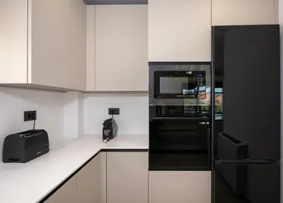 a kitchen with a black refrigerator and white cabinets at Ethernal Luxury Maisonette-Next to the sea in Kamisianá