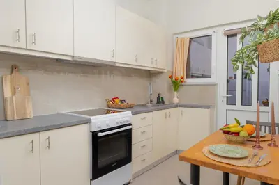 a kitchen with white cabinets and a wooden table at Ela Apartment Chania in Chania Town