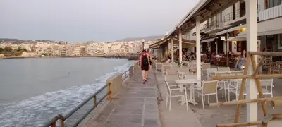 a person walking down a sidewalk next to the water at Ela Apartment Chania in Chania Town