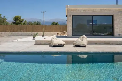 a swimming pool with two stone sculptures next to it at Villa Kumarēs in Alikianós