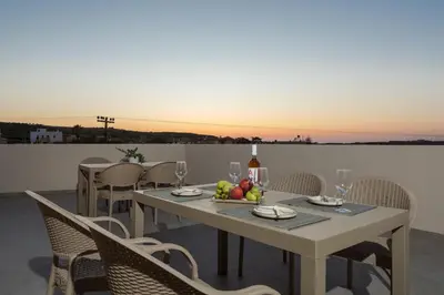a table with a bowl of fruit and a bottle of wine at Fyllianos Apartments in Plátanos