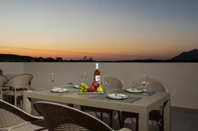 a table with a bottle of wine and a bowl of fruit at Fyllianos Apartments in Plátanos