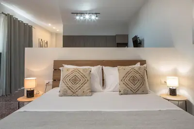 a bedroom with a large white bed with two lamps at Fyllianos Apartments in Plátanos