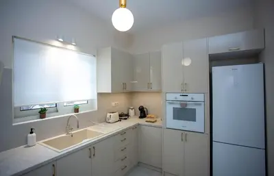 a white kitchen with a sink and a refrigerator at Maira City House in Chania Town