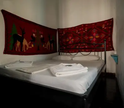 a bed with white towels on it with a red blanket at Pension Nora in Chania Town