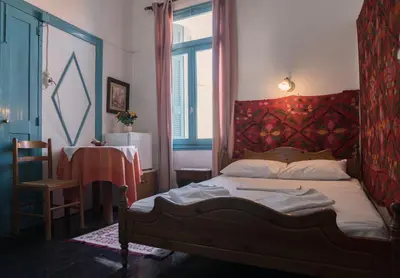 a bedroom with a bed with a red headboard and a table at Pension Nora in Chania Town
