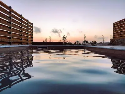 a pool of water with the sunset in the background at LIViT Condo Elafonisi in Agios Padeleimon