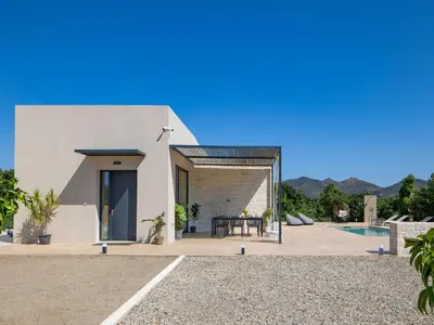 a white house with a patio and a table at PanStel - Villa Aurora with private pool jacuzzi in Ayiá