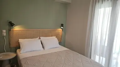 a bedroom with a bed with white pillows and a window at Reflections Apartments in Stalos