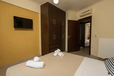 a bedroom with a bed with towels and a flat screen tv at Zen City Beach Apartment in Chania Town