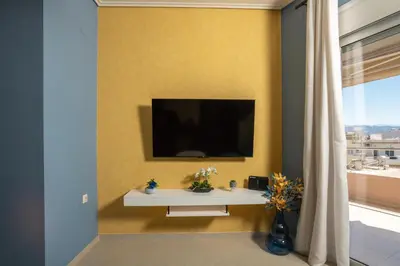a living room with a tv on a wall at Zen City Beach Apartment in Chania Town