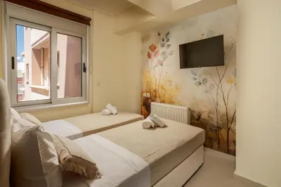 two beds in a room with a tv on the wall at Zen City Beach Apartment in Chania Town
