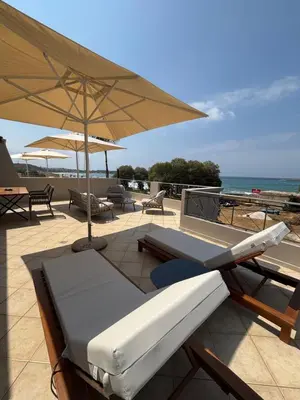 a patio with an umbrella and a bed and chairs at Nea Chora seaside suites in Chania Town