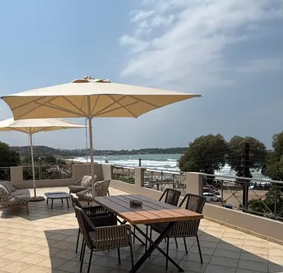 a wooden table and chairs with an umbrella on a patio at Nea Chora seaside suites in Chania Town