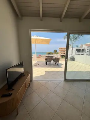 a living room with a view of a patio with an umbrella at Nea Chora seaside suites in Chania Town