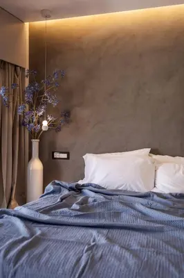 a bed with a blue blanket and a vase with flowers at Kira Elegant City Nest in Chania Town