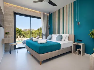 a bedroom with a large bed with a blue wall at PanStel - Villa Solene with private pool in Ayiá