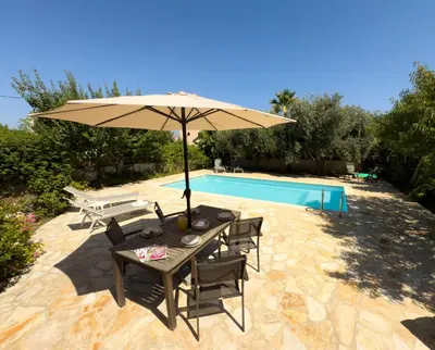 a table with an umbrella next to a pool at Villa Karneios in Tavronitis