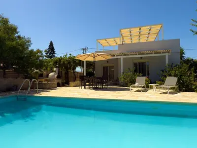 a villa with a swimming pool in front of a house at Villa Karneios in Tavronitis