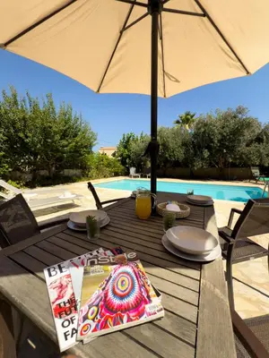 a wooden table with an umbrella next to a pool at Villa Karneios in Tavronitis