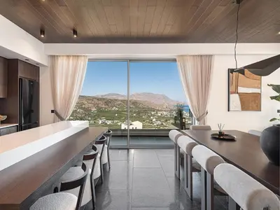 a kitchen with a long bar with chairs and a large window at Villa Thealon I New luxury villa with sea view and private infinity pool in Kissamos