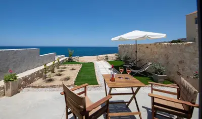 a patio with a table and chairs and the ocean at The Seaside Nest in Chania Town