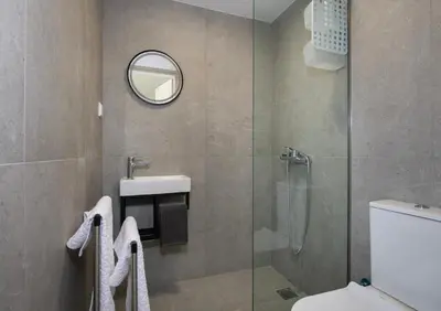 a bathroom with a shower and a sink and a mirror at The Seaside Nest in Chania Town