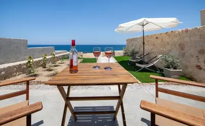 a wooden table with wine glasses and an umbrella at The Seaside Nest in Chania Town