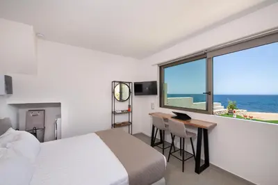 a bedroom with a bed and a desk and a window at The Seaside Nest in Chania Town