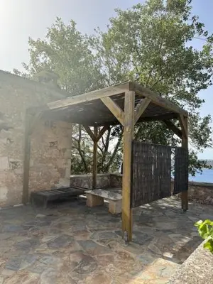 a wooden pavilion on a patio near the water at Casa Aptera in Megála Khoráfia
