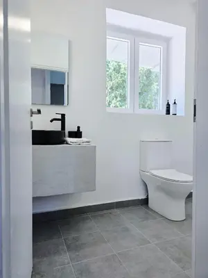 a white bathroom with a toilet and a sink at Suites with Shared Garden Sougia in Moní