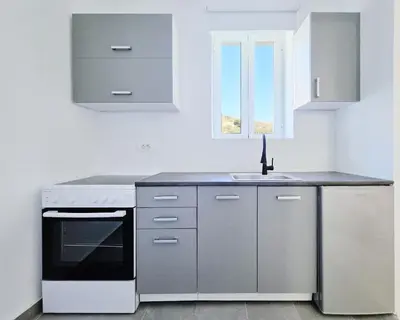 a kitchen with white cabinets and a sink at Suites with Shared Garden Sougia in Moní