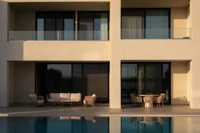 a building with a table and chairs next to a pool at Gemini Villas Chania - Calma & Siesta in Maleme